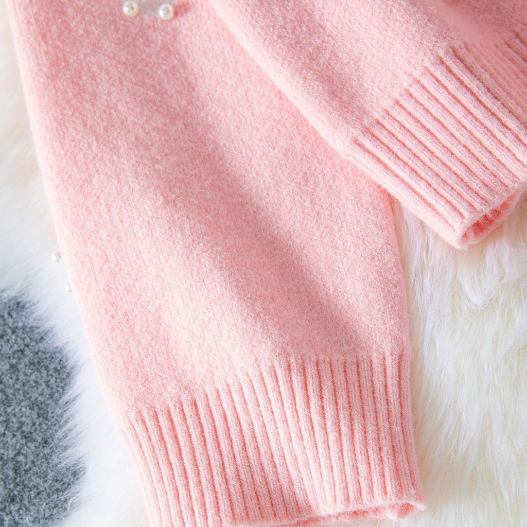 Pink knitted sweater on a fluffy white surface