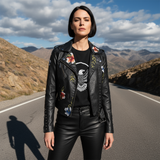 Woman wearing a black leather jacket with floral embroidery standing on a mountain road.