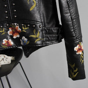 Black leather jacket with floral embroidery on a gray background