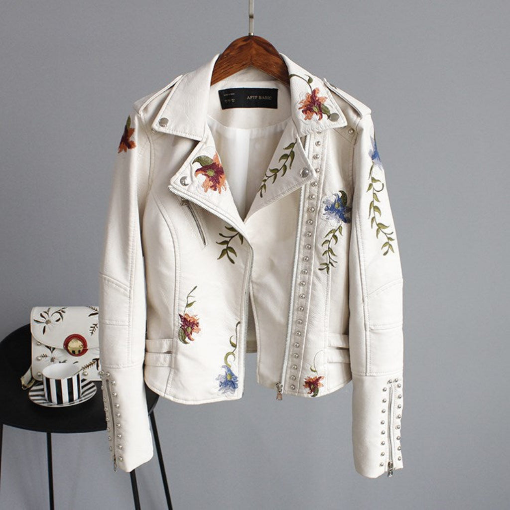 White embroidered jacket on a hanger with a matching bag below.