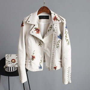 White embroidered jacket on a hanger with a matching bag below.