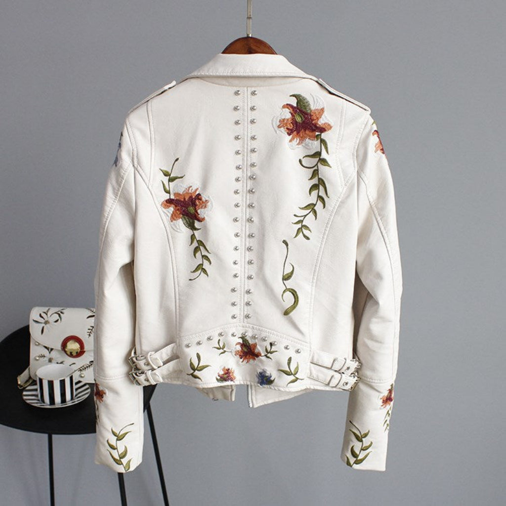 White denim jacket with floral embroidery on a gray background