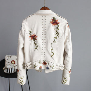 White denim jacket with floral embroidery on a gray background