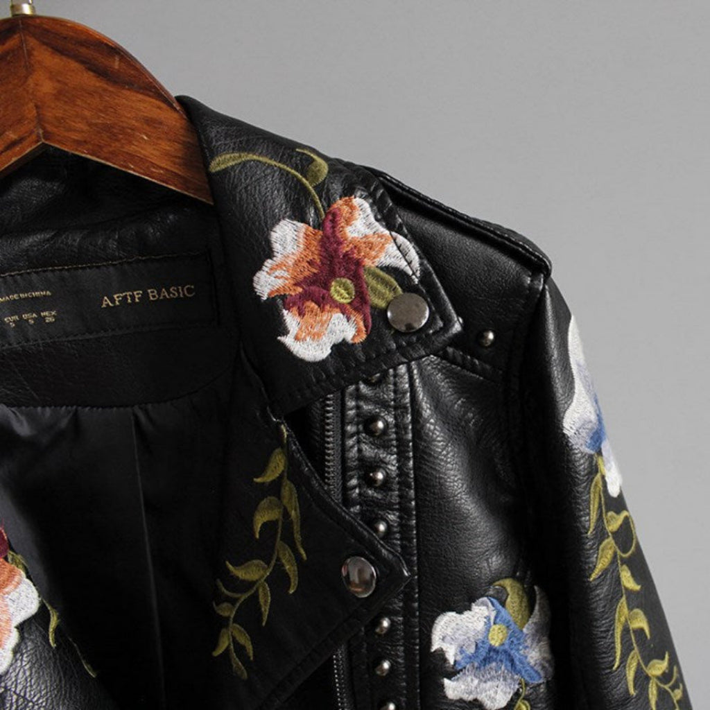 Black leather jacket with floral embroidery on a gray background