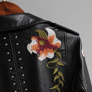Black leather jacket with floral embroidery and studs on a gray background