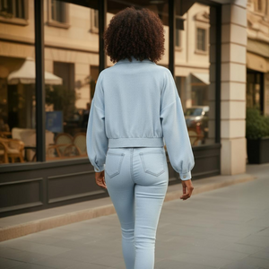 Person wearing a light blue outfit walking on a city street.