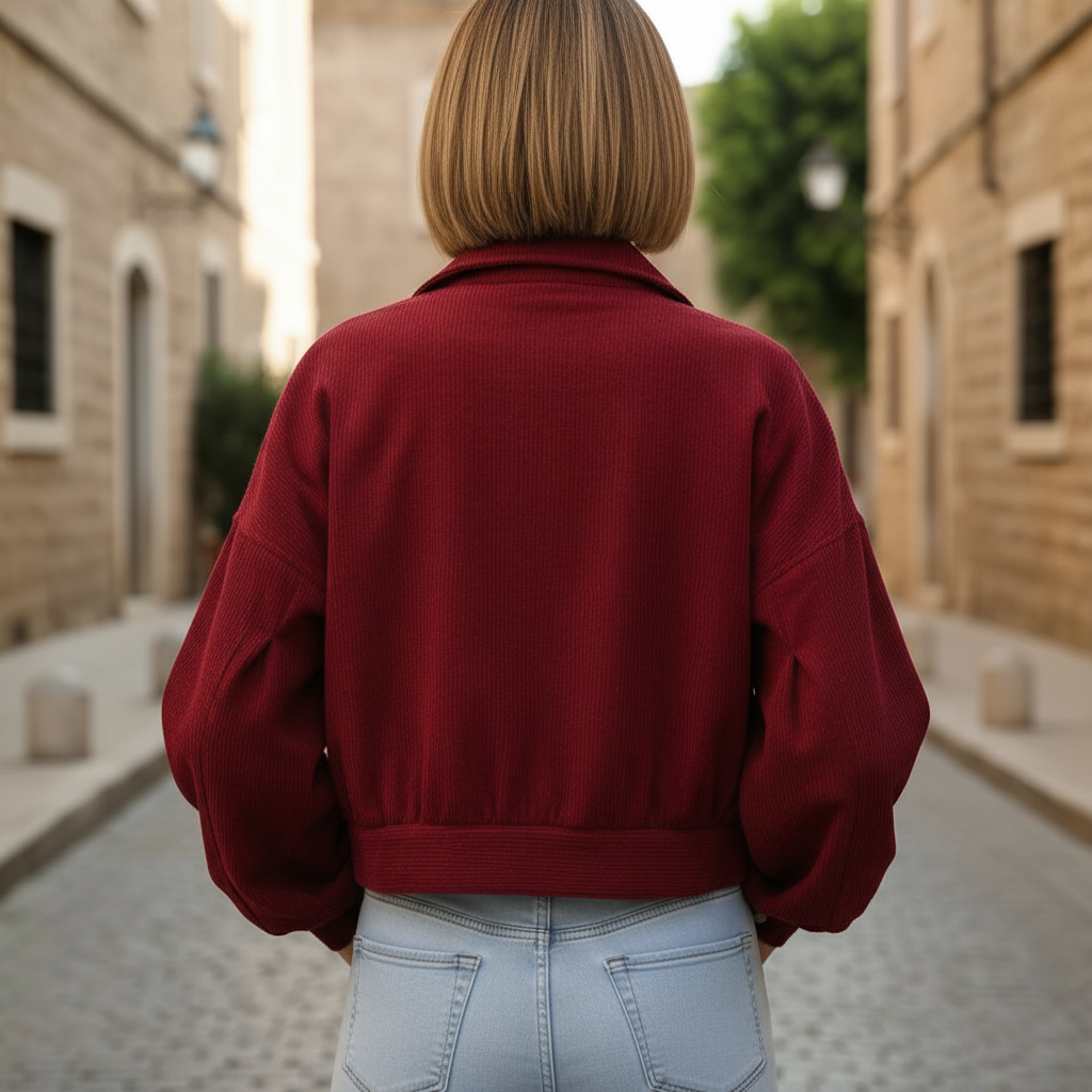 Person wearing a red jacket walking down a narrow street with stone buildings.