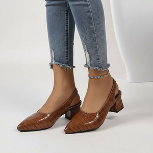 Brown pointed-toe shoes worn with blue jeans on a white background