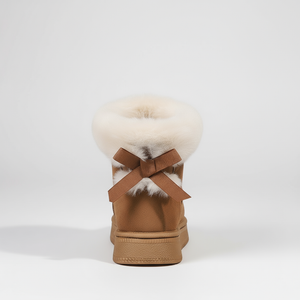 Tan shoe with white fur pom-pom and brown bow on a white background