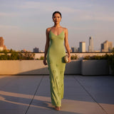 Woman in a green dress standing on a rooftop with city skyline in the background