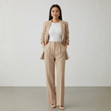 Woman wearing a beige suit with a white top against a plain background