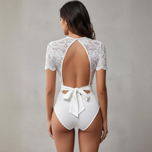 White lace bodysuit with open back and bow detail on a neutral background