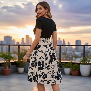 Woman in a black and white floral dress standing on a rooftop with city skyline in the background