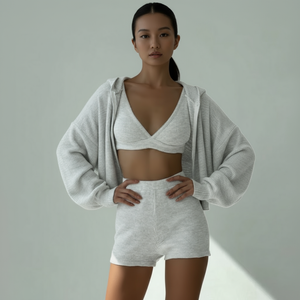 Woman wearing a white knit outfit with a gray cardigan on a plain background