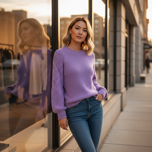 Woman in a purple sweater and blue jeans standing in front of a store window.