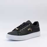 Black sneaker with gold accents on a light gray background