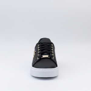 Black sneaker with gold accents on a light gray background