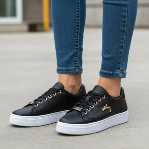 Black sneakers with white soles worn with blue jeans on a pavement background