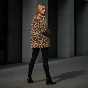 Woman wearing a leopard print coat standing on a city street.