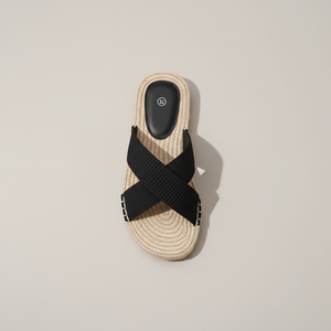 Beige sandal with black cross strap on a beige background