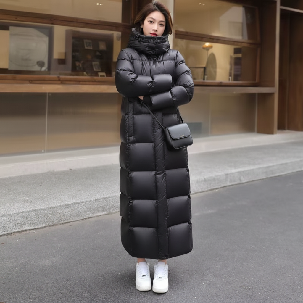 Person wearing a long black puffer coat standing on a street.