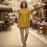 Woman in a yellow top and beige pants walking on a street with blurred background