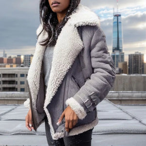 Close-up of a woman wearing a grey shearling jacket with white lining on a snowy rooftop.