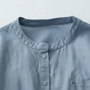 Close-up of a light blue shirt with a collar and buttons on a gray background