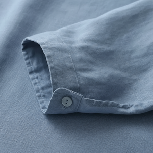 Close-up of a rolled-up sleeve on a light blue shirt with a button.