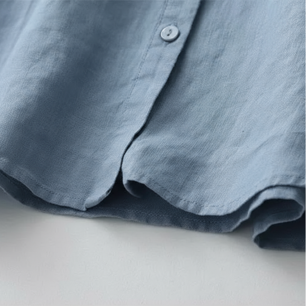 Close-up of a blue shirt with a button on a light gray background