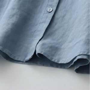 Close-up of a blue shirt with a button on a light gray background
