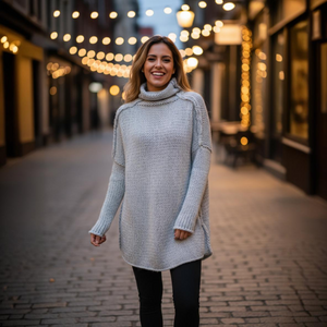 Woman wearing a gray sweater standing on a street with blurred lights in the background