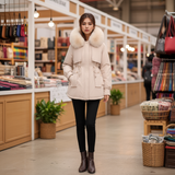 Woman wearing a beige parka with fur hood in a store setting