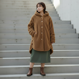 Woman wearing a brown hooded fleece coat standing on outdoor steps.