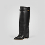 Black knee-high boot with a gold buckle on a light gray background