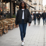 Woman walking on a city street with outdoor cafe tables in the background