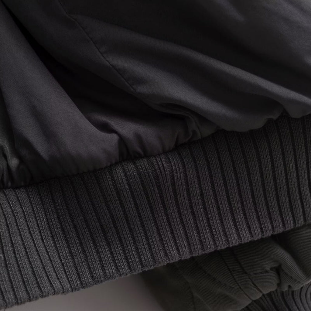 Stack of dark clothing items including a jacket and a sweater.