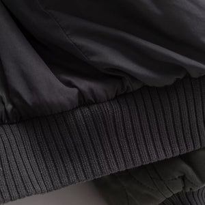 Stack of dark clothing items including a jacket and a sweater.