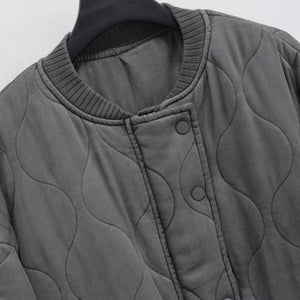 Gray quilted jacket on a hanger against a light gray background