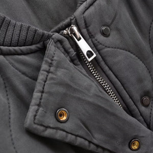 Close-up of a gray jacket with zipper and button details