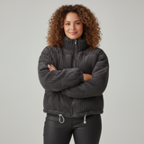 Woman wearing a dark gray quilted jacket with a plain background