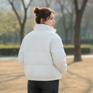 Woman wearing a white puffer jacket standing outdoors with trees in the background