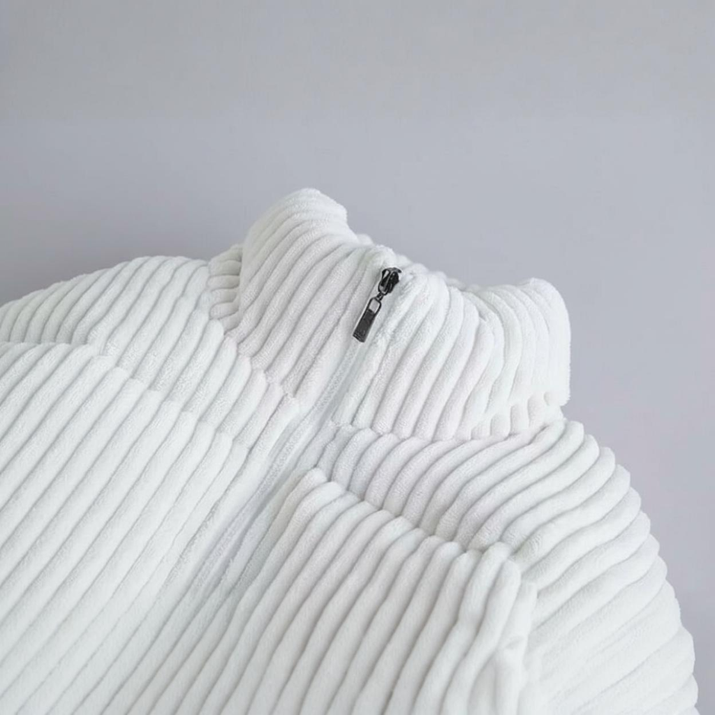 Close-up of a textured white garment with a zipper on a light gray background