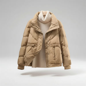 Beige puffer jacket over a white sweater on a neutral background