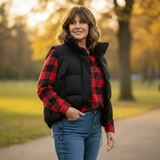 Woman wearing a red and black plaid shirt with a black vest in a park setting