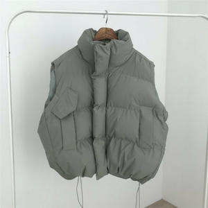 Gray puffer vest hanging on a rack against a white background