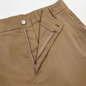 Close-up of brown pants with a button and zipper on a white background