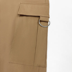 Close-up of beige pants with a belt and buckle on a white background
