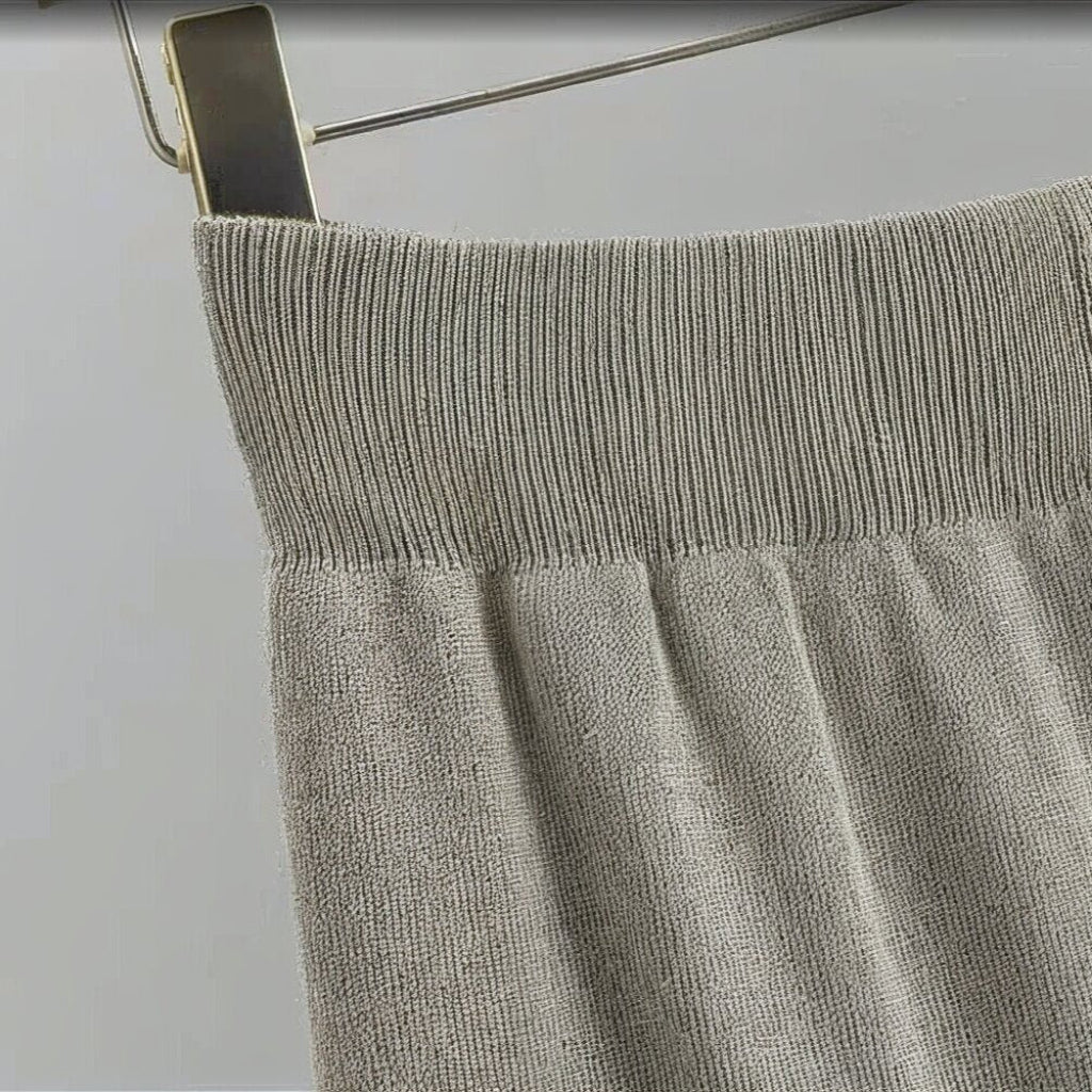 Gray knit sweater on a hanger against a white background