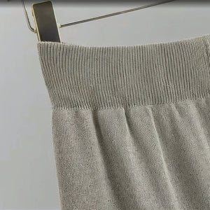 Gray knit sweater on a hanger against a white background